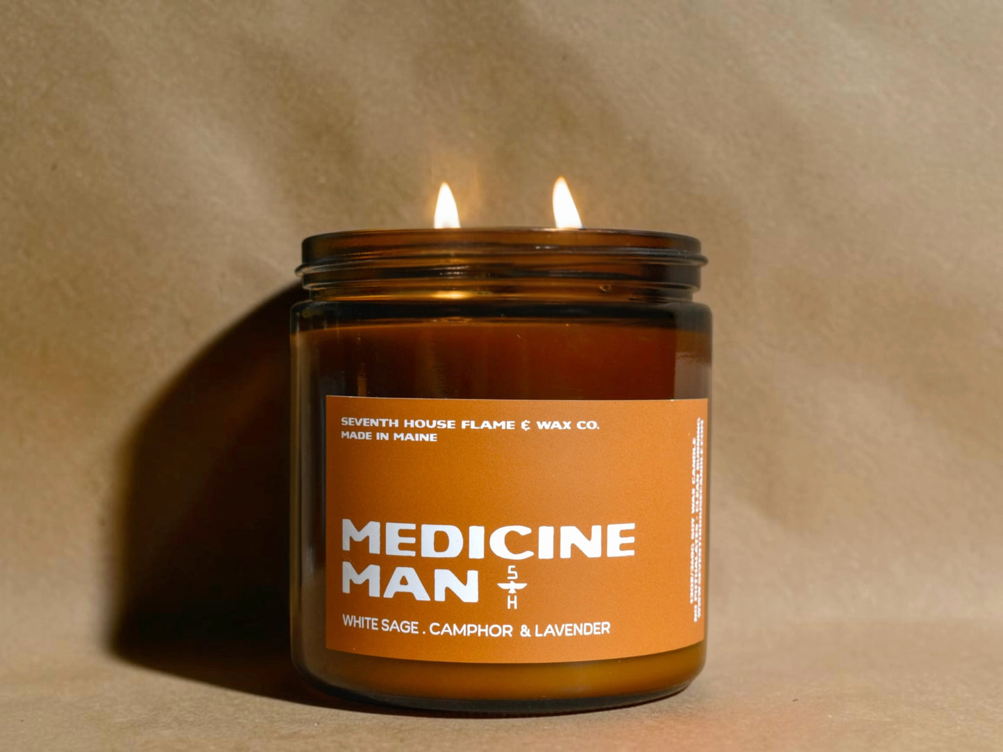 Candle in a jar labeled 'Medicine Man' with an orange label on a beige background