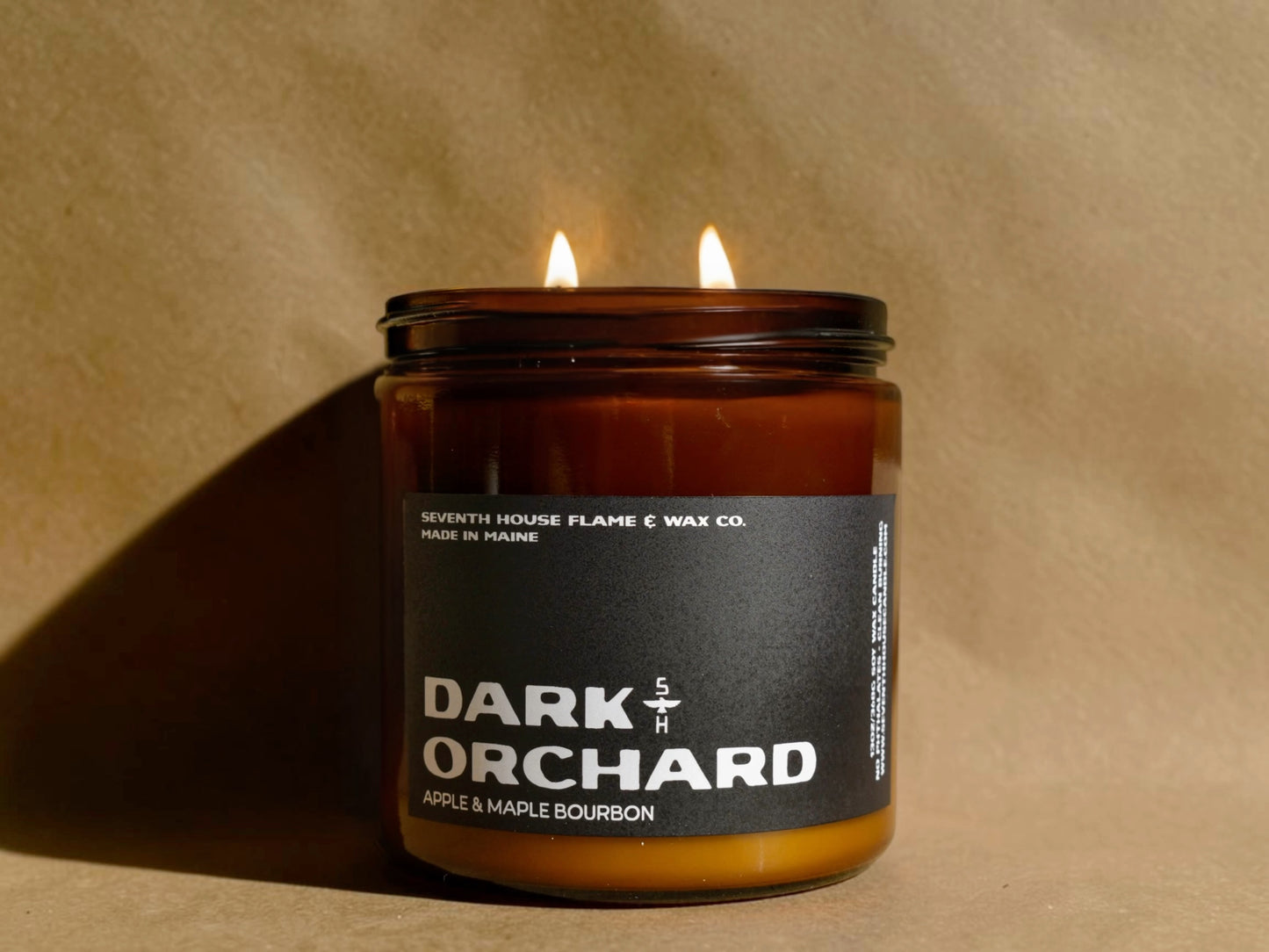 Candle in a jar labeled 'Dark Orchard' on a beige background