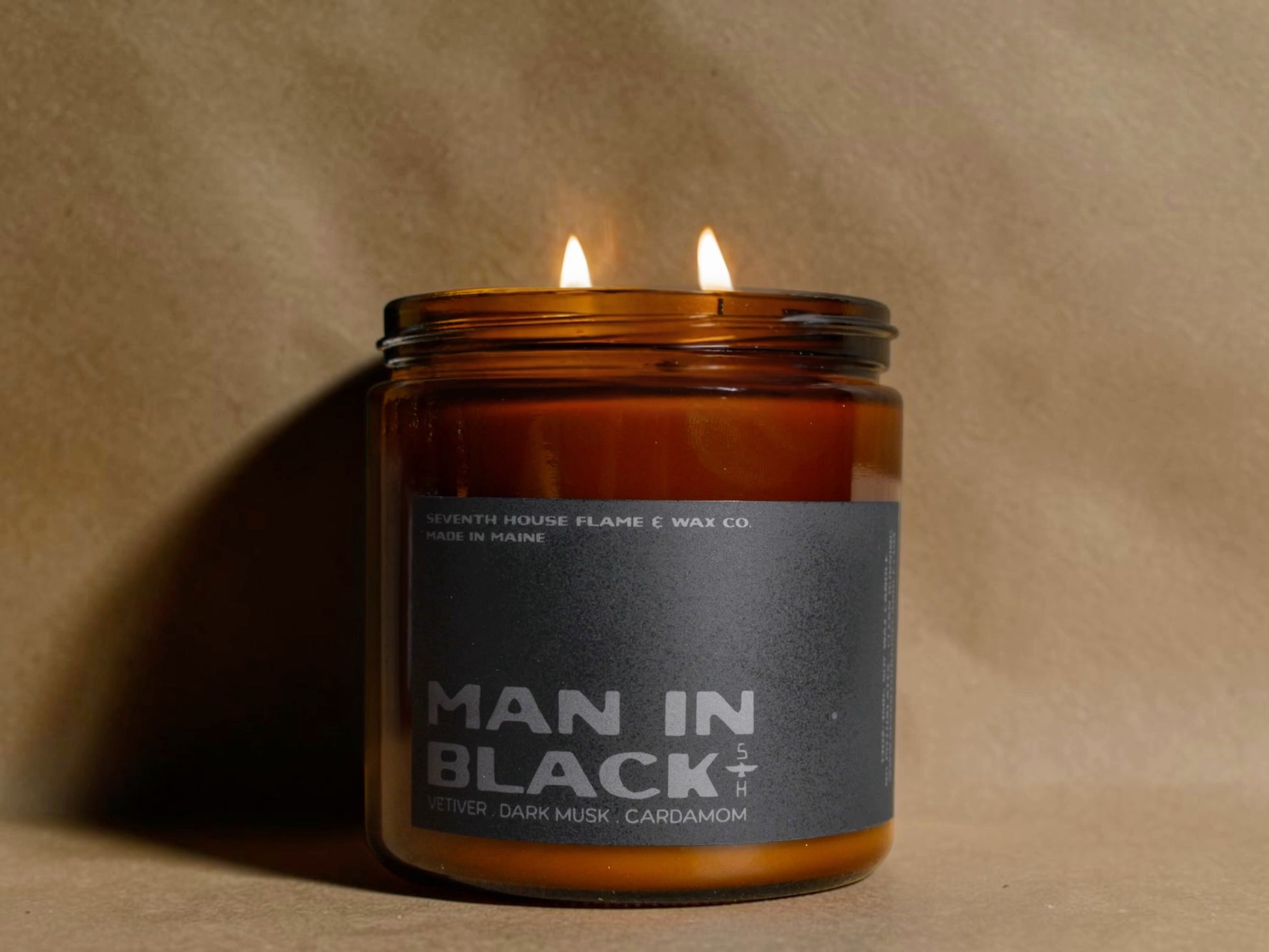 Candle in an amber jar labeled 'Man in Black' on a beige background