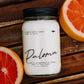 Candle labeled 'Paloma' with grapefruit on a wooden surface