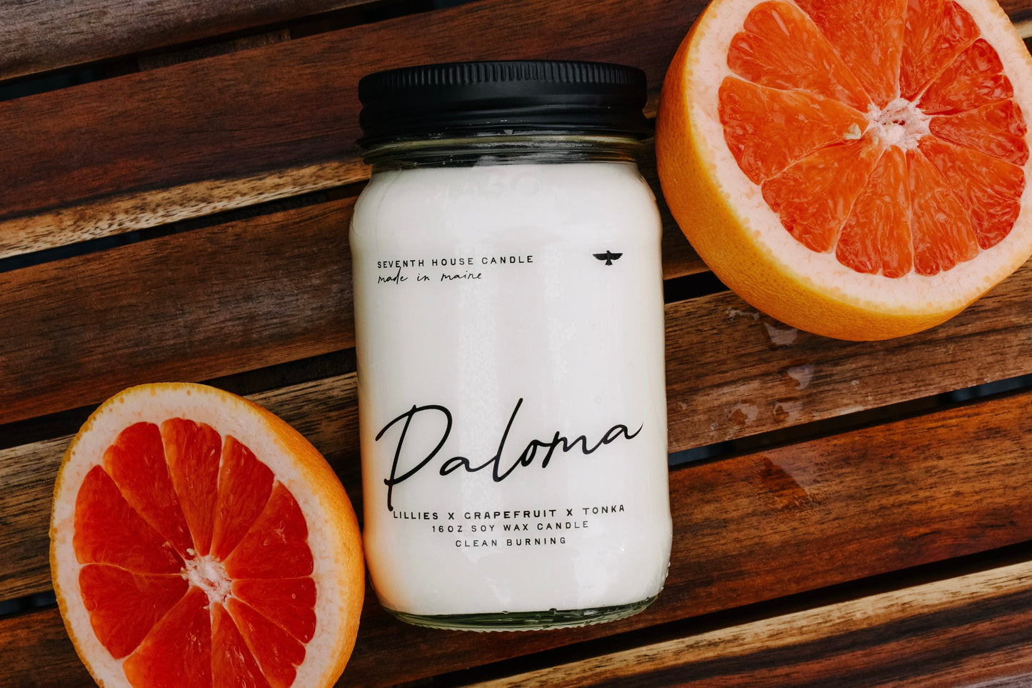 Candle labeled 'Paloma' with grapefruit on a wooden surface