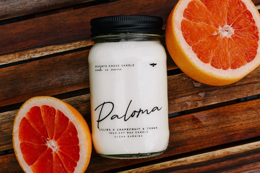 Candle labeled 'Paloma' with grapefruit on a wooden surface