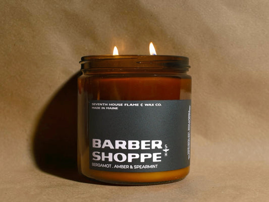 Candle in a jar labeled 'Barber Shoppe' on a beige background
