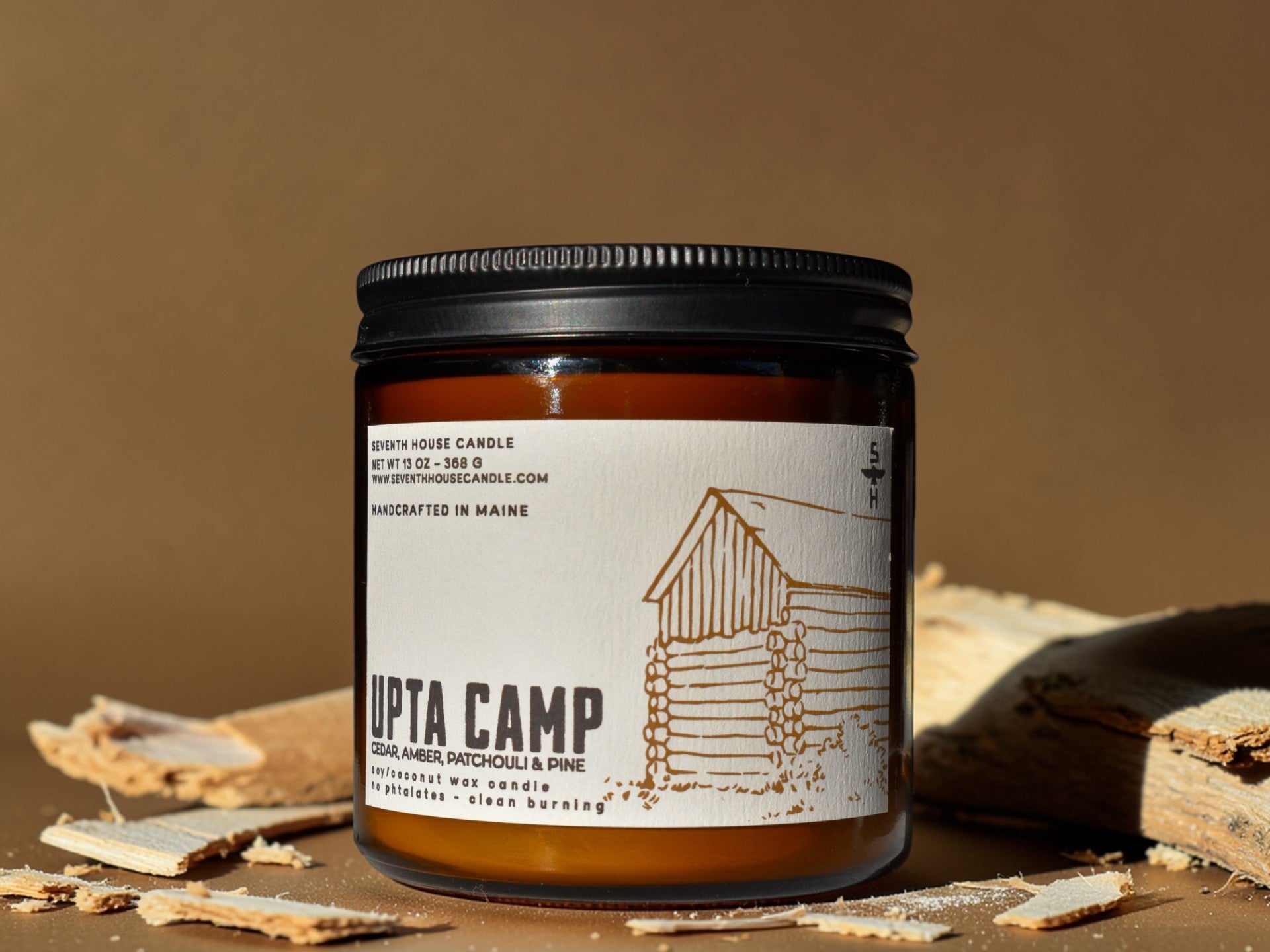 Candle jar with 'Upta Camp' label on a brown background