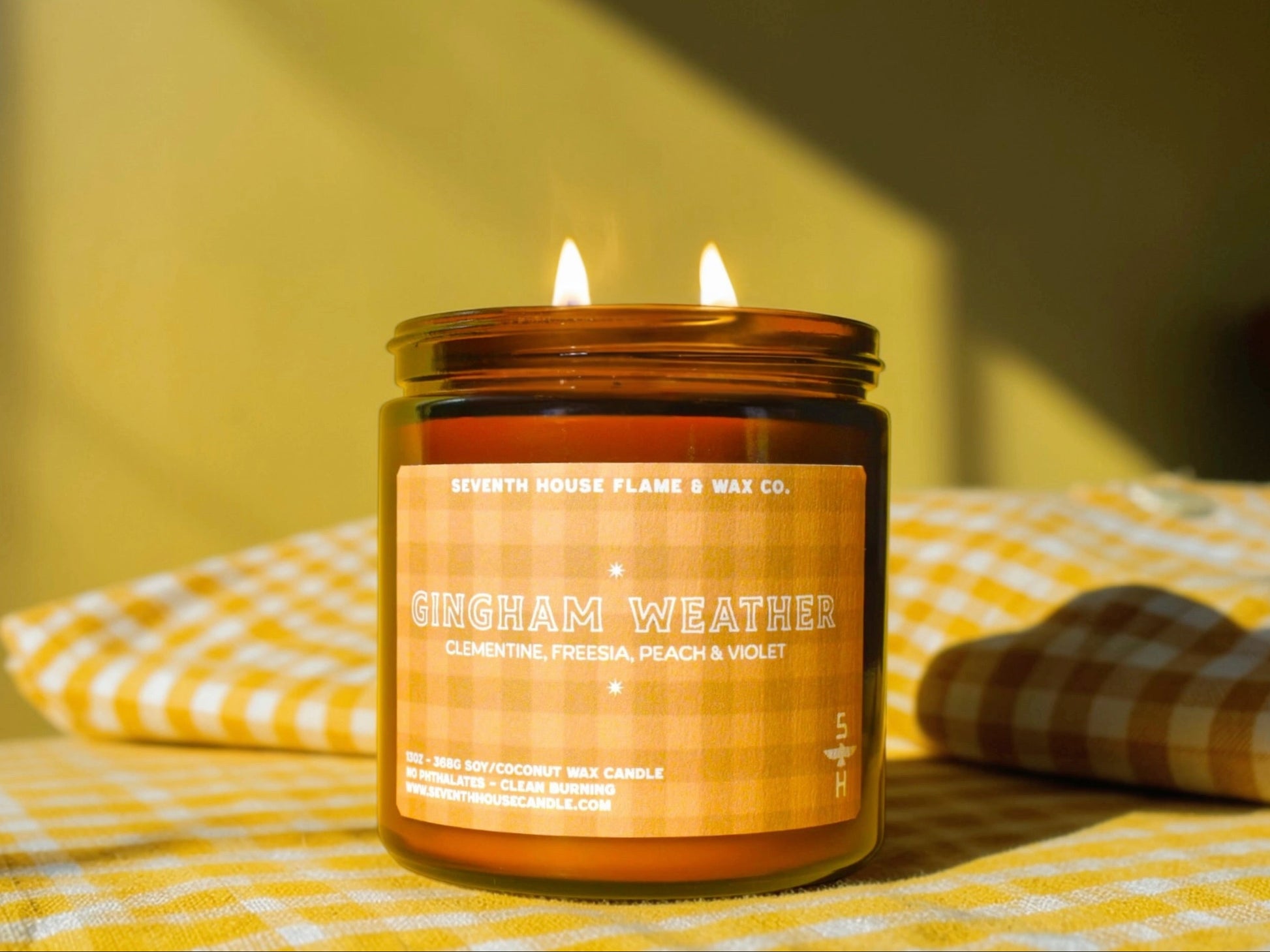 Candle labeled 'Gingham Weather' on a yellow checkered tablecloth