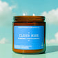 Candle in an amber jar with a blue label against a sky background