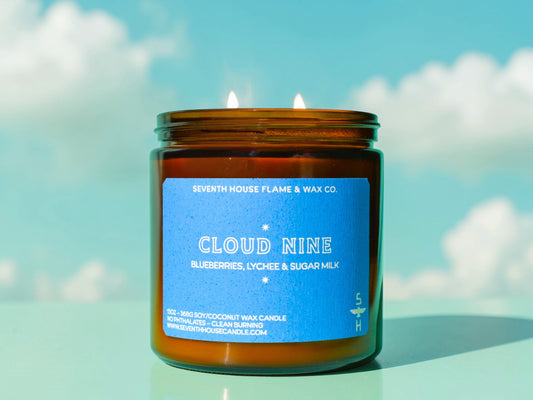Candle in an amber jar with a blue label against a sky background