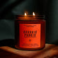 A lit amber glass jar candle with a red-orange label reading 'Bunkin' Punkin' and 'Pimpelip & Research,' set on a wooden surface against a dark draped background.