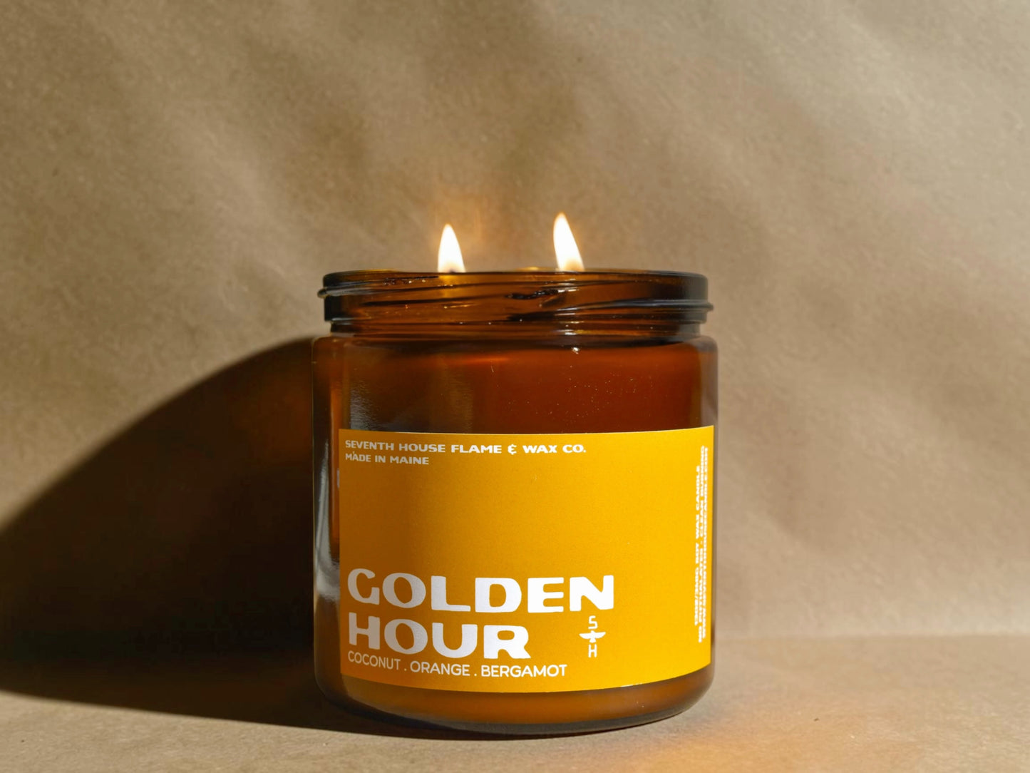 Candle in a glass jar with a yellow label on a beige background
