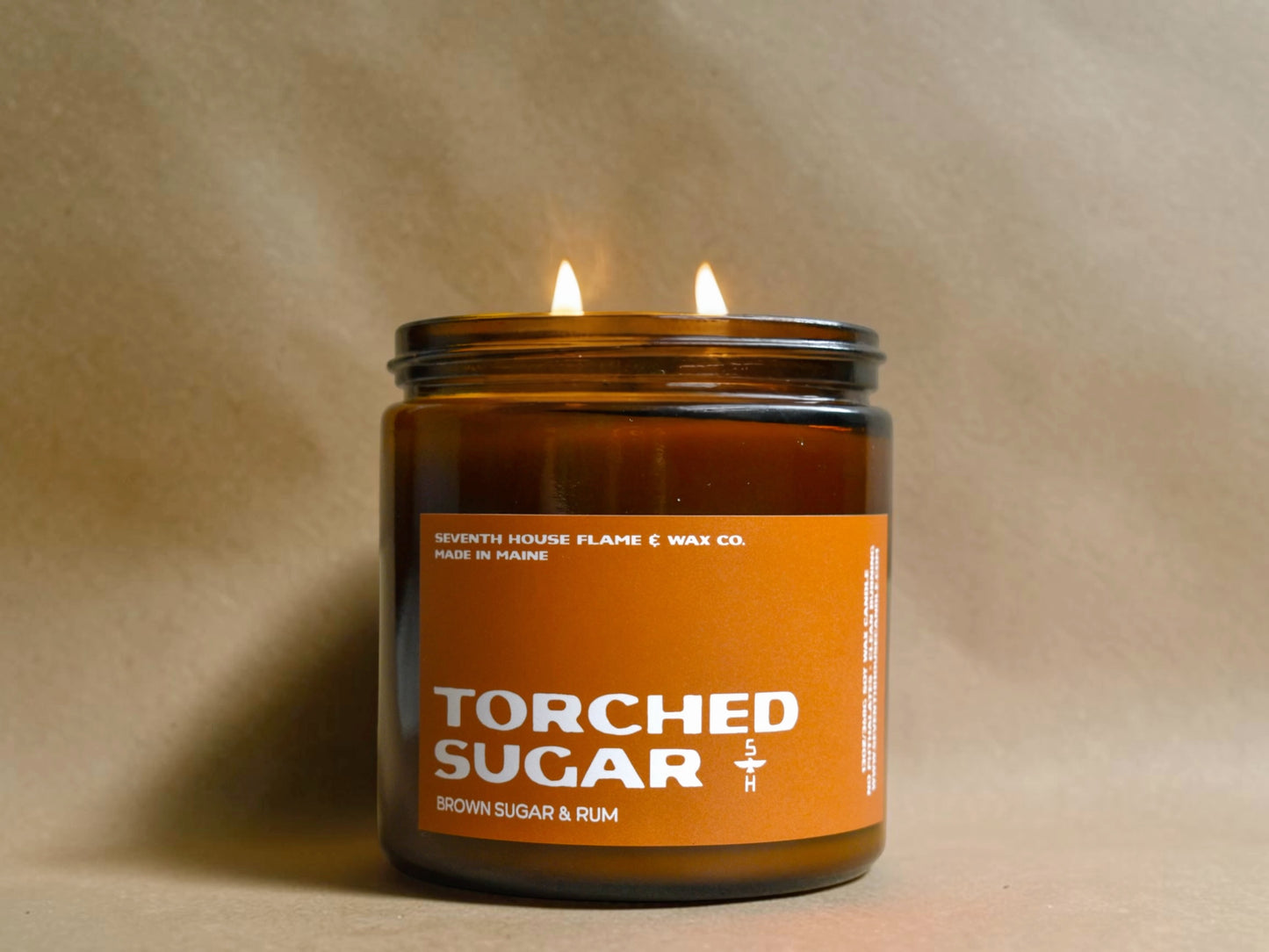 Candle in a jar labeled 'Torched Sugar' with an orange label on a beige background