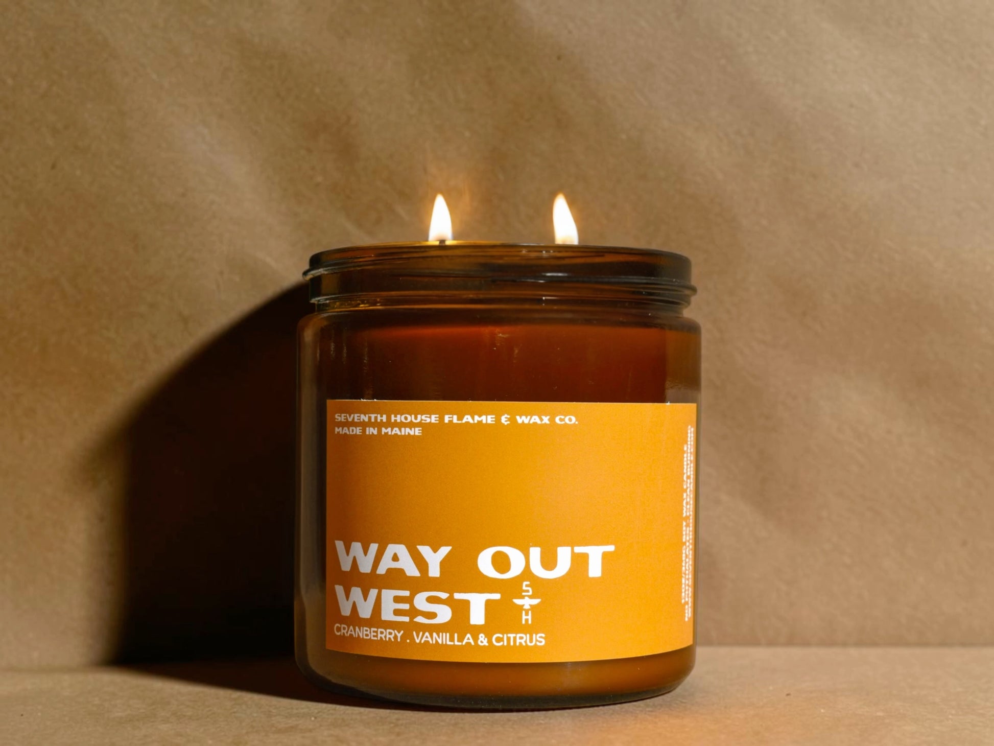 Candle in a glass jar with an orange label on a beige background