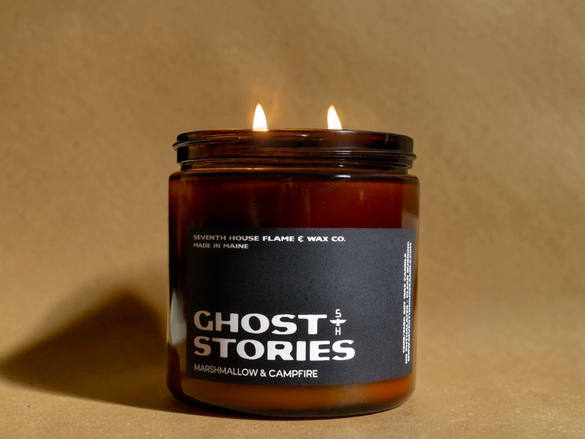 Candle in a jar labeled 'Ghost Stories' on a beige background